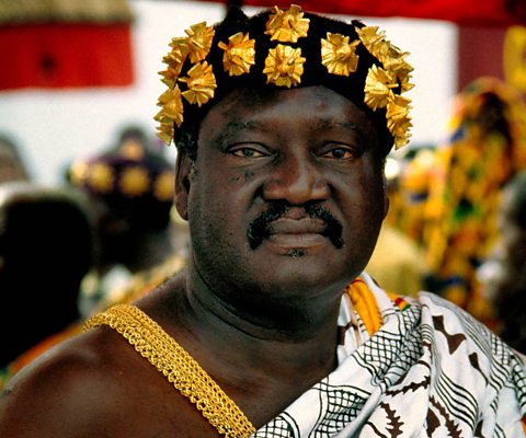 An Asante chief dressed in robes and crown.