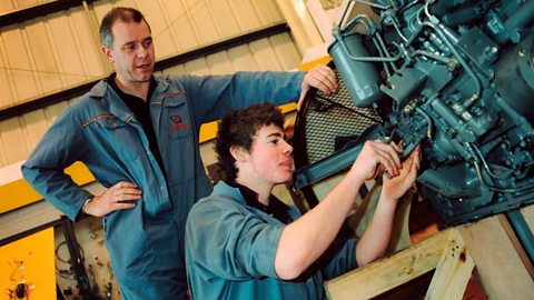 An apprentice using a machine in workshop