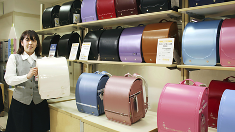 A woman stands showing traditional Japanese backpacks