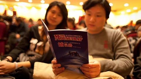Getty Audience read the playbill ahead of a performance of Christie’s The Mousetrap, at the Shanghai Lyceum Theatre (Credit: Getty)