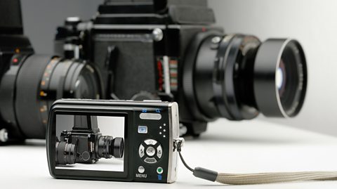 A photograph of a large camera is displayed on the screen of a small digital camera.