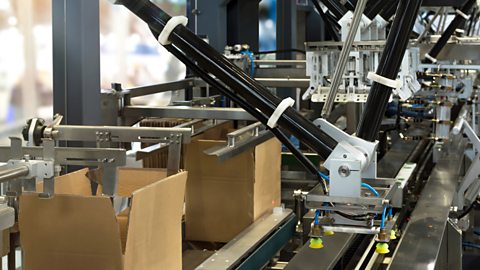 An automated conveyor system in a factory featuring a robot arm and cardboard packaging.