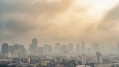 A congested city skyline with a hazy fog of air pollution casting over the buildings.