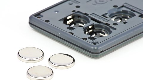 Lithium button-cell batteries displayed on a white background alongside a calculator.