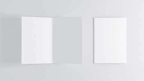 A blank opened greeting card that has been scored next to a closed blank greeting card.