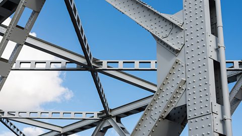 A large, grey, detailed construction showing metal bracing against the blue sky.