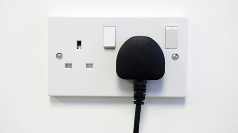 A British double electrical plug socket with one of the plugs switched on.