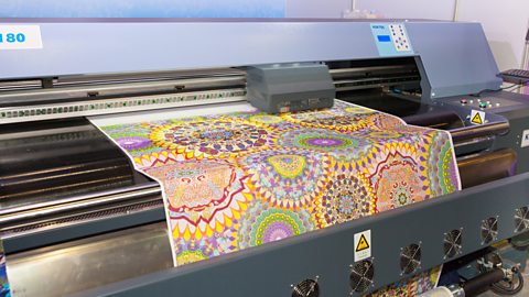 A machine showing digital printing of a detailed, colourful pattern on a fabric.