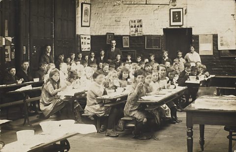 Children eating school dinner in a classroom during World War One