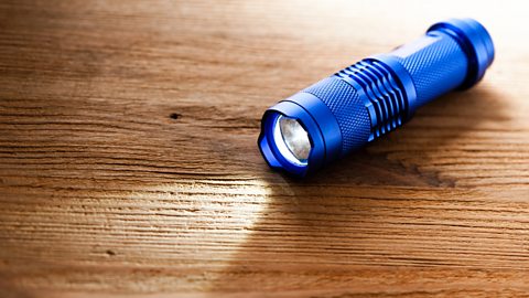 A blue pocket LED torch placed on a wooden table.