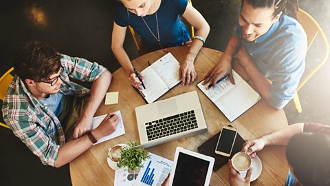 Group of friends studying and chatting. Laptop, phone and tablet in the middle of table.