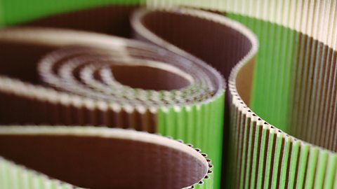 A close-up view of rolled up corrugated card in green and brown.