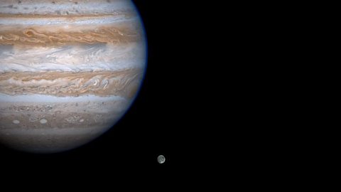 A photo of Jupiter and its largest moon Ganymede, taken from the Cassini spacecraft