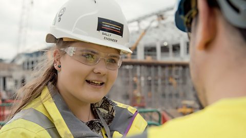 A young woman wears a hard hat on a building site