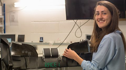 a young woman, Amy, shows a formula 1 front wing piece of carbon.