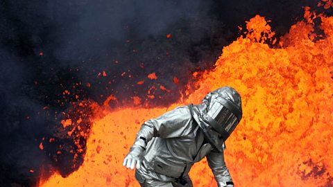 A figure in a safety suit in front of molten lava. 