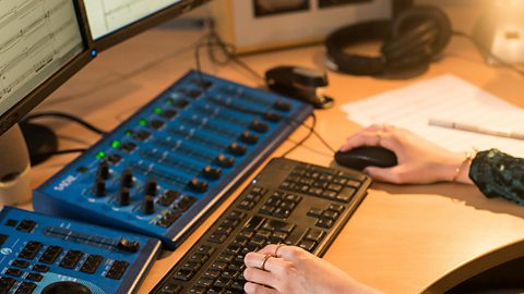 Hands of a young woman, Grace, typing on a computer keyboard to write music