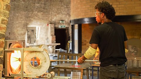 A young man, Jahday, working on one of his pieces of glass art