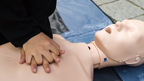 A young woman, Khadija, performing a heart massage on a CPR dummy