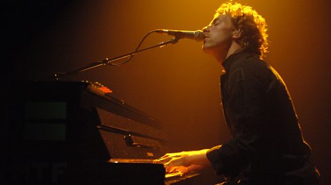 Chris Martin from Coldplay singing and playing the piano