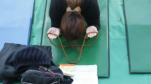 Getty Images A mother prays for her children taking the College Scholastic Ability Test at Chogey temple in Seoul, South Korea (Credit: Getty Images)