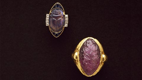 Two gold and precious stone Art Nouveau rings are displayed side by side.