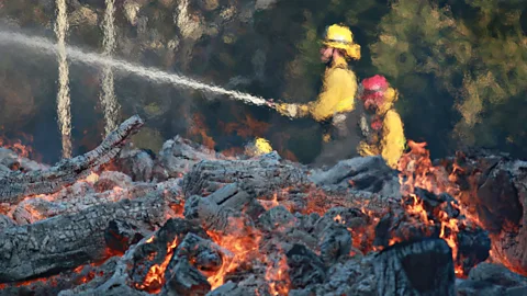 Getty Firefighters battle the Woolsey Fire in Malibu in November 2018; the California wildfire season used to end in early autumn, but that’s changing (Credit: Getty)