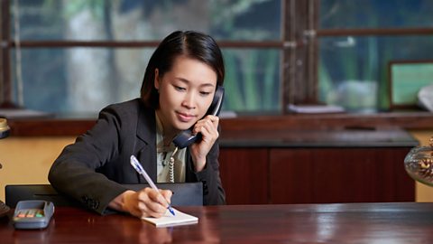 A receptionist on the phone, taking notes.