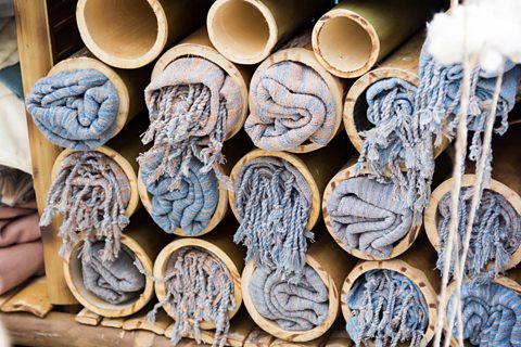 Bamboo fibre blankets are shown rolled up and stored within wooden tubes.