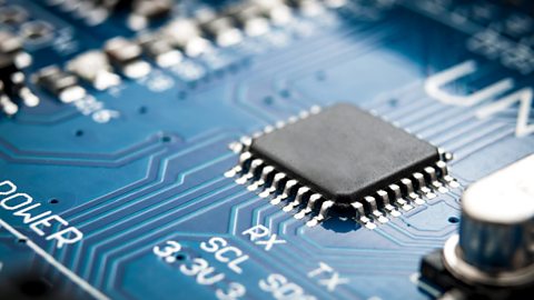 A close-up of a square microprocessor in place on a blue circuit board.