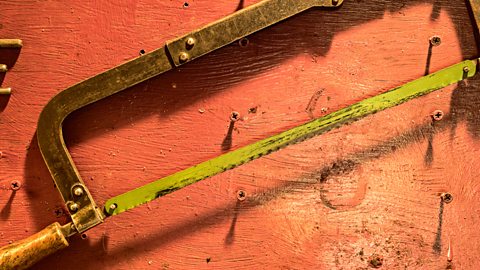 Hacksaw with yellow blade and on red bench