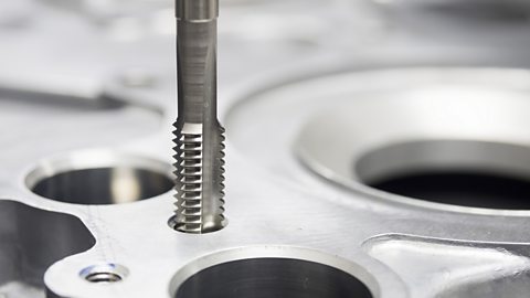 A close-up of the tapping process to add a thread to a metal component.