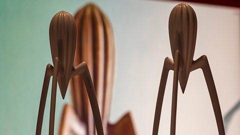 Two wooden, abstract lemon juicers sit on top of their boxes.