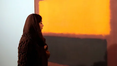 Getty Images An Iranian woman looks at Sienna, Orange and Black on Dark Brown by Mark Rothko during an exhibition of modern art at TMOCA in 2015 (Credit: Getty Images)