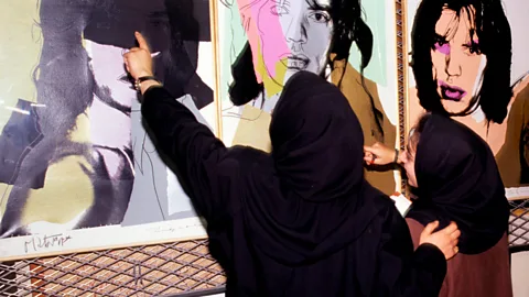 Getty Images Two female staff at the Tehran Museum of Contemporary Art (TMOCA) examine portraits of Mick Jagger by Andy Warhol in the cellar of the museum in 1993 (Credit: Getty Images)