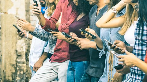 A group of young people using smartphones outdoors.