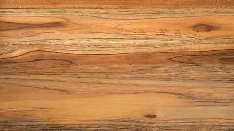The texture of teak - an array of orange brown colours with dark knots and lines.