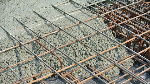 Wet concrete being poured on a steel reinforcement mesh to form strong floor slabs.