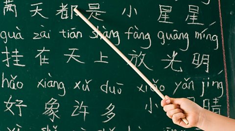 Someone pointing at Chinese characters on a chalkboard