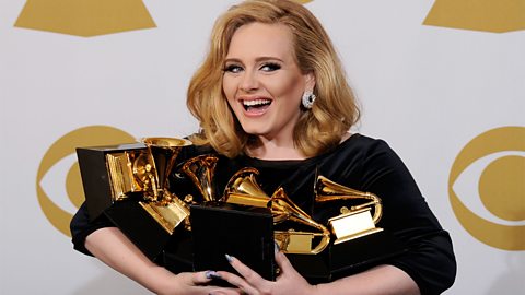 A photograph of Adele with her six Grammy awards.