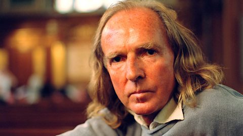 A photograph of John Tavener sat in a church.