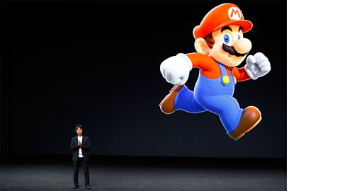 A member of the Nintendo company and a projected image of Super Mario.