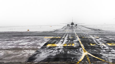 An airport runway in snow and fog