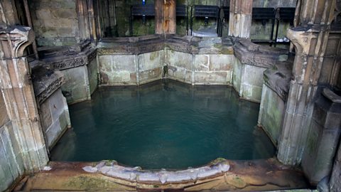 A pool surrounded by an ornately carved border and columns