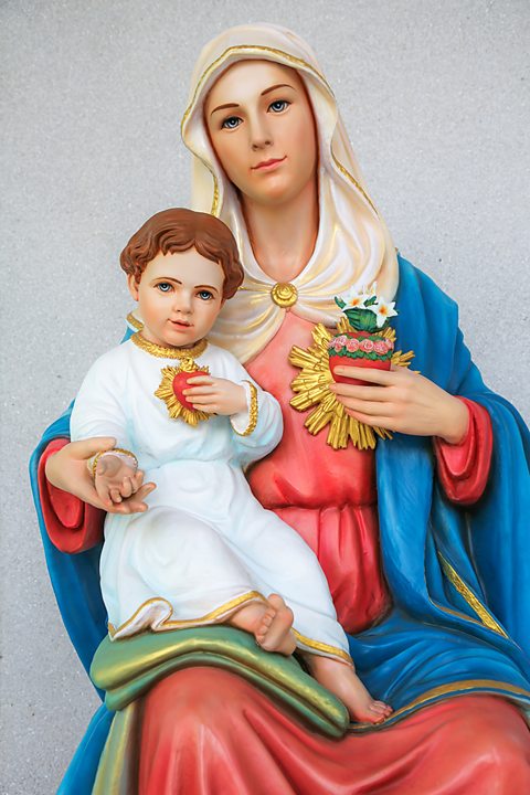 Statue of The Virgin Mary with baby Jesus in her lap. They are both clutching the Sacred Heart symbol to their chests