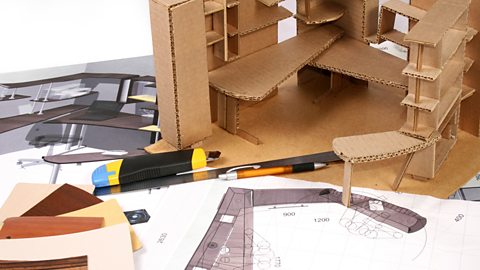 A sketch model a room made of corrugated cardboard sits on top of the drawn design.