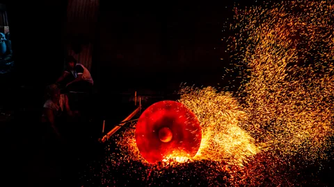 Getty Images A worker heats a metal plate as they make traditional gong instruments in Indonesia (Credit: Getty Images)