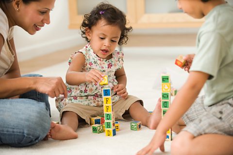 A little girl stacking bricks with her little brother