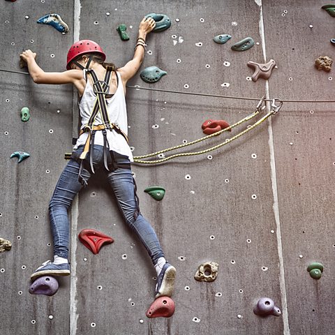 A teenage girl on a climbing wall.