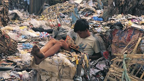 Young boy reading in a rubbish dump in City of Manila, Philippines